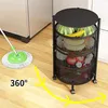 A black three-tier rolling cart filled with fruits and vegetables is shown in a kitchen setting next to a mop. Produktbild-Vorschau