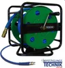 A blue air hose is wound around a green reel on a black metal stand. The reel has a crank handle and the brand name 'PREBENA' is visible. Náhľad obrázku produktu