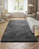 A living room with a large gray rug in the center, a white sofa, a chair, and a window with white curtains. Anteprima dell’immagine prodotto