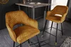 Two mustard yellow velvet bar stools with diamond quilting and gold foot caps are placed next to a high bar table in a modern interior setting. Produktbild-Vorschau