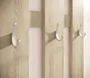 A close-up view of a wooden coat rack with three silver hooks. Produktbild-Vorschau