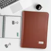 A brown conference folder is placed on a white surface next to a laptop, a notebook, and a cup of coffee. Náhľad obrázku produktu