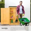 A man is standing next to a wooden garden shed, pushing a wheelbarrow filled with a green hose. Produktbild-Vorschau