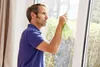 A man is cleaning a window with a cloth. Podgląd zdjęcia produktu