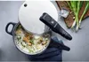 A pressure cooker with food inside, next to ingredients like green onions and salt. Produktbild-Vorschau