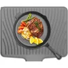A steak dinner is served on a cast iron pan placed on a grey silicone drying mat. Produktbild-Vorschau