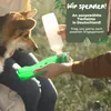 A person is pouring water from a bottle into a green dog bowl for a dog. Produktbild-Vorschau
