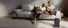A couple relaxing on a couch in a modern living room, with an air purifier in the foreground. Produktbild-Vorschau