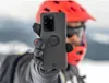 A person in winter gear holding up a smartphone case. Produktbild-Vorschau