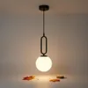 A modern pendant light with a black metal frame and an opal glass sphere hangs from the ceiling. Náhled obrázku produktu
