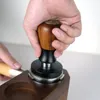 A hand is using a coffee tamper on a wooden stand. Náhled obrázku produktu