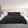 A black duvet cover and pillow set laid out on a bed in a modern bedroom. Voir les images du produit
