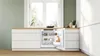 A built-in refrigerator in a modern kitchen, with the door open to reveal contents. Náhled obrázku produktu