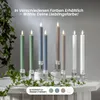 Several LED candles in different colors are displayed on a table with greenery. The text indicates they are available in various colors. Podgląd zdjęcia produktu