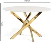 A round dining table with a marble-effect top and a gold-colored criss-cross base, shown from a side angle. Anteprima dell’immagine prodotto