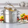 A stack of stainless steel pots with a colander insert filled with pasta, placed on a kitchen counter with vegetables and herbs in the foreground. Produktbild-Vorschau