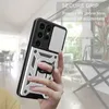 A hand holding a silver and black phone case with a ring holder, with a blurred indoor background. Produktbild-Vorschau