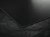 A close-up, angled view of a black induction hob with a matte finish, resting on a textured dark surface. Anteprima dell’immagine prodotto