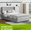 A bedroom scene featuring a bed with bedding and pillows, a floor lamp, and a window with curtains in the background. Produktbild-Vorschau