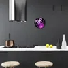 A modern kitchen with dark gray cabinets, a stainless steel range hood, and a white countertop. A round wall clock with a purple butterfly design is mounted on the wall. Produktbild-Vorschau