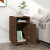 A brown wooden cabinet with wheels is placed next to a white sofa with a blanket draped over it. The cabinet has an open door revealing books inside. A vase with a plant and a clock are on top of the cabinet. Náhľad obrázku produktu