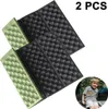 Two folding seat cushions and a child sitting in a campsite. Produktbild-Vorschau