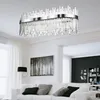 A modern living room with a white sofa, a black floor lamp, and a large black and white forest artwork on the wall. A rectangular chandelier hangs from the ceiling. Produktbild-Vorschau