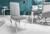 A close-up of a gray upholstered dining chair with silver legs in a luxurious dining room setting. Náhled obrázku produktu