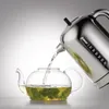 A chrome kettle pouring hot water into a glass teapot with mint leaves. Anteprima dell’immagine prodotto
