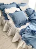 A bed with blue and white ruffled bedding. Podgląd zdjęcia produktu