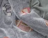 A close-up view of a soft, plush children's blanket with a pattern of sports balls, including a soccer ball and an American football. Produktbild-Vorschau