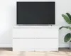 A white TV stand with a black TV on top, placed against a white wall with a plant to the right. Náhľad obrázku produktu