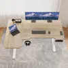 A modern L-shaped standing desk with dual monitors, a laptop, keyboard, mouse, and headphones, set up in a home office environment with a rug and curtains. Podgląd zdjęcia produktu