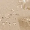 Water droplets on a beige fabric surface, with a clear plastic bottle pouring liquid. Produktbild-Vorschau