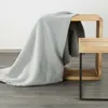 A light gray blanket is draped over a wooden cube-shaped stool with a black metal frame. Náhľad obrázku produktu
