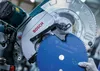 A close-up view of a miter saw blade being held near the saw itself. Voir les images du produit
