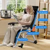 A woman is sitting in a reclining chair indoors, reading a book. The chair is shown with labels indicating its support features. Náhled obrázku produktu