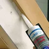 A hand is using a caulking gun to apply sealant between two wooden beams. Anteprima dell’immagine prodotto