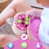 A child is holding a pink and white electronic toy with pop-it buttons, sitting on a rug. Produktbild-Vorschau