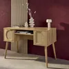A wooden desk with rattan accents is displayed against a red wall and a slatted wooden panel. Produktbild-Vorschau