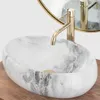 A close-up view of a marble basin with a gold faucet. Produktbild-Vorschau
