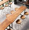 A modern dining or bar area with a long wooden table and several stools. Produktbild-Vorschau