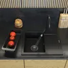 A black granite sink with a pull-out faucet and a dish rack with tomatoes on a kitchen countertop. Produktbild-Vorschau
