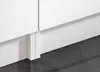 Close-up of the base of white kitchen cabinets resting on a dark gray tiled floor, with white plinth molding. Produktbild-Vorschau