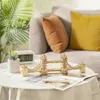 A wooden model of the Tower Bridge sits on a round table with a white tablecloth, next to a small potted plant and a digital clock. In the background, a sofa with pillows is visible. Anteprima dell’immagine prodotto