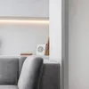 A close-up view of a modern living room interior, focusing on a grey sofa and a shelf with decorative items. Anteprima dell’immagine prodotto