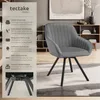 A grey upholstered chair with black metal legs is shown in a room setting with bookshelves and decor in the background. A text-heavy informational graphic is on the left side of the image. Produktbild-Vorschau