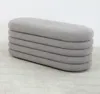 A light gray boucle ottoman with a layered, rounded design is shown against a white and light gray background. Produktbild-Vorschau