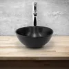 A black ceramic vessel sink with a chrome faucet against a concrete-like wall. Náhled obrázku produktu