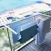 A clothes drying rack is set up on a balcony overlooking a beach and ocean. Voir les images du produit